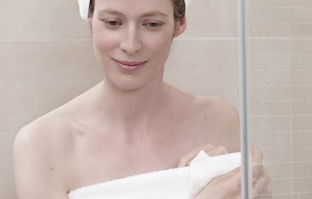 Mujer tras la ducha, envuelta en una toalla, con un turbante en la cabeza.