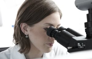 Científica mirando al microscopio