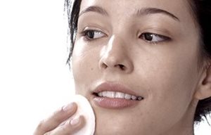 Mujer tonificándose la piel facial con una gasa de algodón