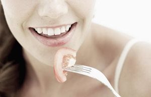 Mujer sosteniendo un tenedor con un trozo de tomate.