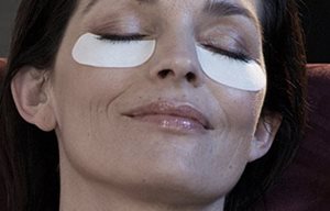 Cara femenina con gasas para el cuidado de los párpados inferiores.