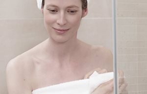 Mujer tras la ducha, envuelta en una toalla, con un turbante en la cabeza.