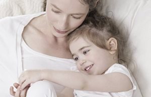 Madre e hija tendidas una al lado de la otra, abrazadas.