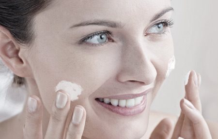 Mujer aplicándose crema en la cara.
